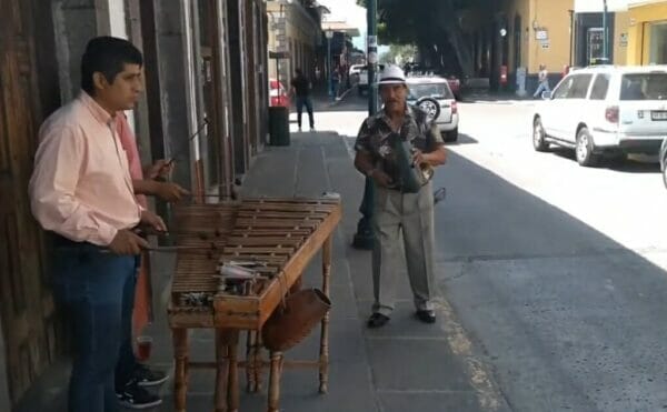 男性3人が道の歩道でマリンバを演奏している
