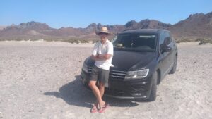 メキシコの観光ガイド岩﨑功がラパスで車の前で腕を組んでいる