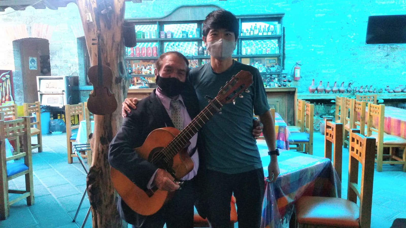 メキシコの観光ガイド岩﨑功がギターを持ったメキシコ人男性と肩を組んでいる