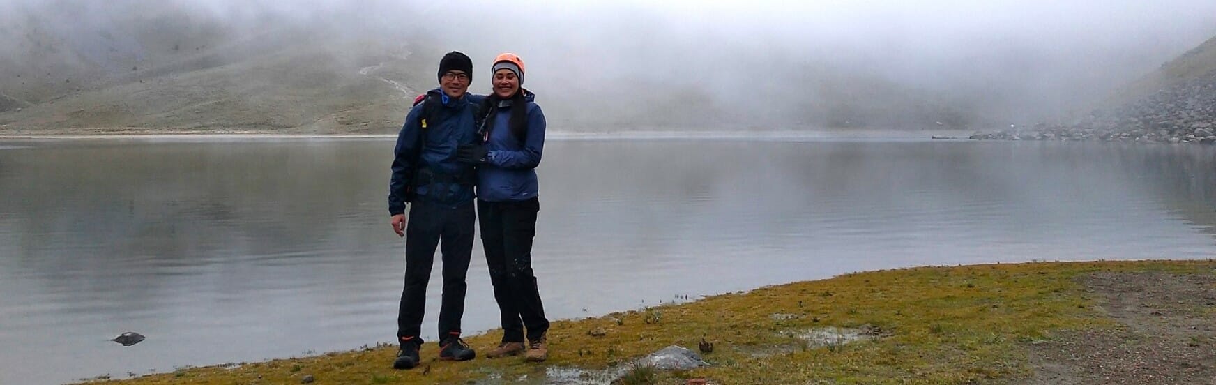 A couple standing by a foggy lake