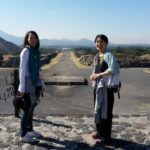 2人の女性がテオティワカン遺跡の全景をバックにピラミッドの上に立っている