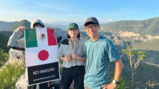 女二人男一人が雄大なサボテンの渓谷を背景に立っている